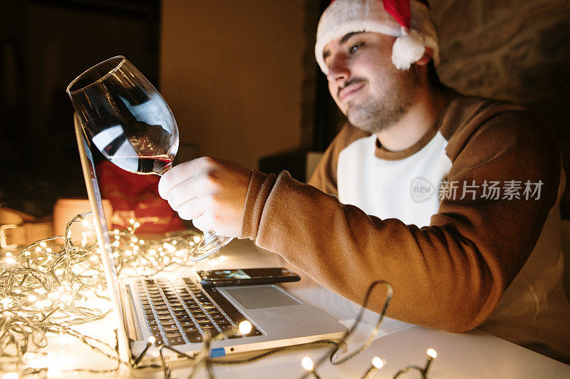 Young man video calling on Christmas and toasting with a wine glass